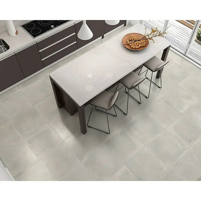 BHS Showroom Pavimento porcelánico Madox - 45 x 45 cm, Gris, Mate - Un diseño de cocina elegante con una isla moderna, taburetes de bar y baldosas de gran formato en tonos neutros.