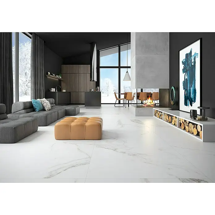 BHS Showroom Pavimento porcelánico Palatina - 120 x 120 cm, Blanco, Mate, Rectificado - Una sala de estar luminosa con un sofá gris moderno, un taburete marrón y suelos de mármol blanco, creando un ambiente elegante.