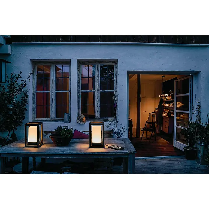 Ledvance Smart+ WiFi Außenlaterne - L x B x H: 12 x 12 x 20,3 cm, Grau, IP44 - Zwei elegante Tischleuchten mit warmem Licht auf einem rustikalen Holztisch, die eine gemütliche Atmosphäre im Freien schaffen.