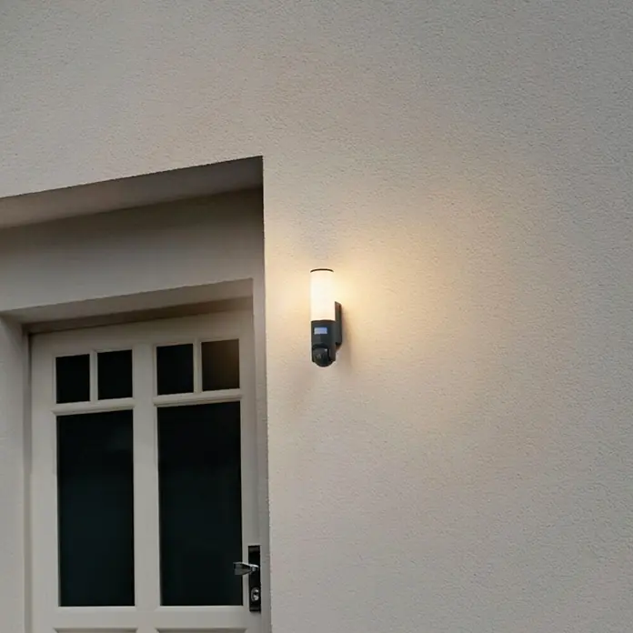 Ledvance Smart+ WiFi LED-Außenwandleuchte - 12 x 8 x 32 cm, Kamera, Dunkelgrau, IP44 - Ein Außenleuchte mit Bewegungsmelder an einer hellen Hauswand neben einer Tür.