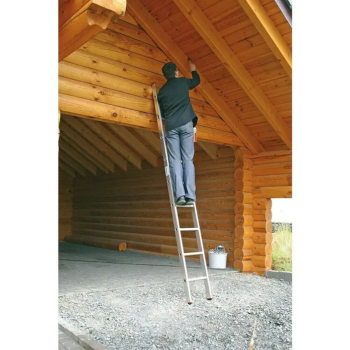 Krause Monto Anlegeleiter Sibilo - Anzahl Tritte: 9 Stk., Arbeitshöhe: 3,6 m, Belastbarkeit: 150 kg, Aluminium - Mann auf einer Leiter, der das hölzerne Vordach eines Blockhauses streicht. Die Leiter ist aus Aluminium und hat mehrere Sprossen.