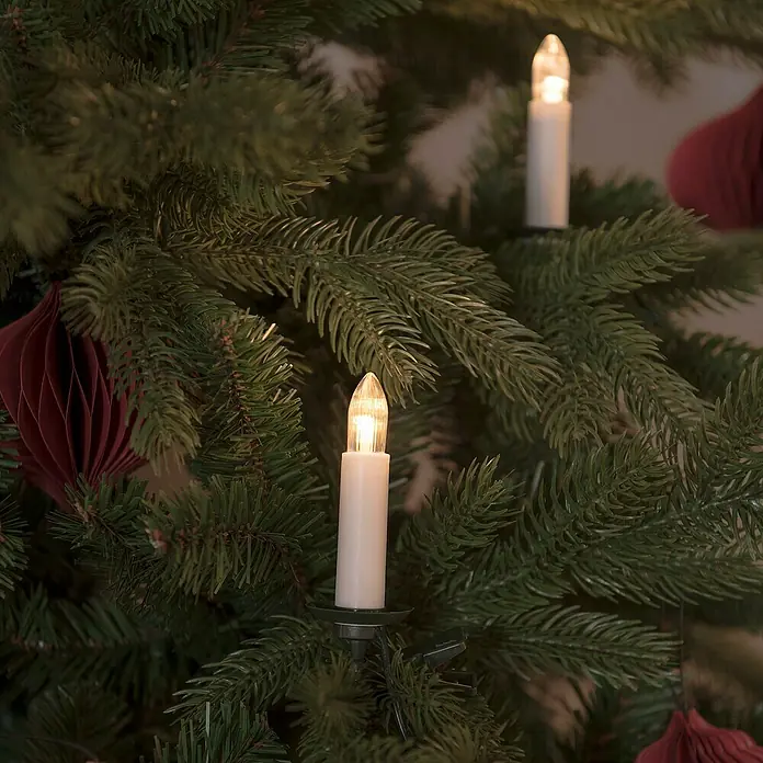 Konstsmide LED-Weihnachtskerzen - 15,5 m, Weiß, Lichtfarbe: Bernstein, Anzahl Leuchtmittel: 16 Stk., IP20 - Weihnachtsbaum mit festlichen Kerzenlichtern und roten Schmuckelementen für eine stimmungsvolle Atmosphäre.