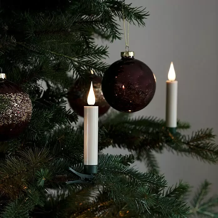 Konstsmide LED-Weihnachtskerzen - 1,8 cm, Weiß, Lichtfarbe: Warmweiß, 10 Stk., IP20 - Weiße LED-Kerzen mit warmen Flammen, an einem grünen Weihnachtsbaumzweig befestigt.