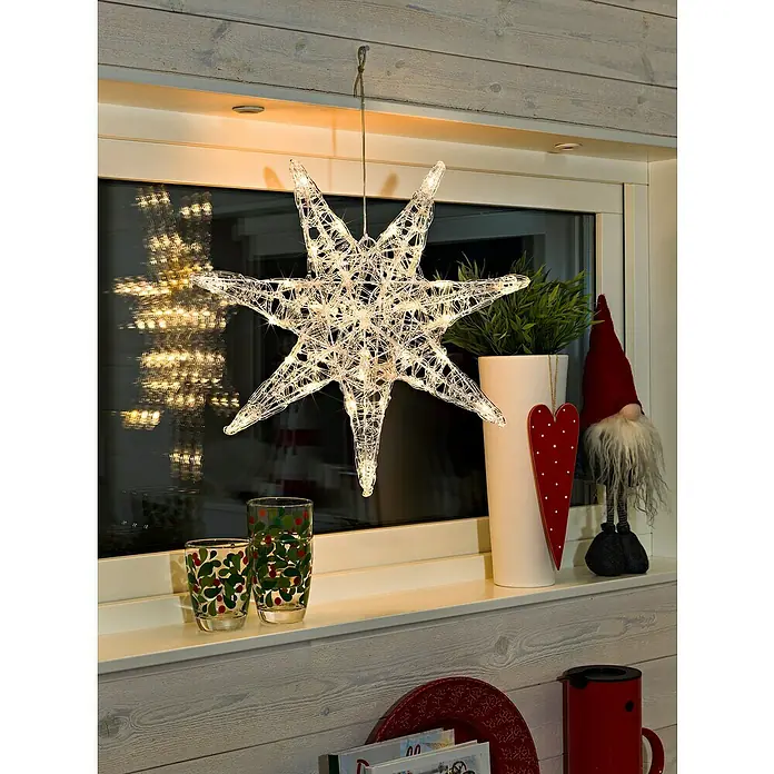 Konstsmide LED-Stern - 45 cm, Farblos, Lichtfarbe: Warmweiß, IP20, Netzbetrieben - Festliche Szene mit einem leuchtenden Stern, dekorativen Gläsern und einem bezaubernden Weihnachtswichtel auf einer Fensterbank.