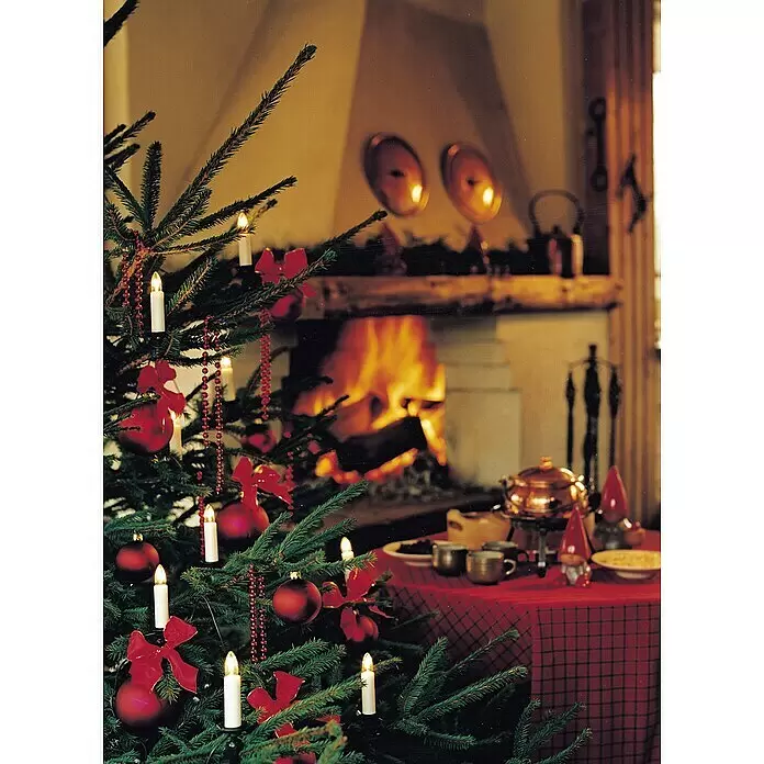 Konstsmide Baumkerzen-Set - 35 Stk., Glühlampe - Festlich geschmückter Weihnachtsbaum mit Kerzenlichtern, roten Kugeln und Schleifen in gemütlichem Raum am Kamin.