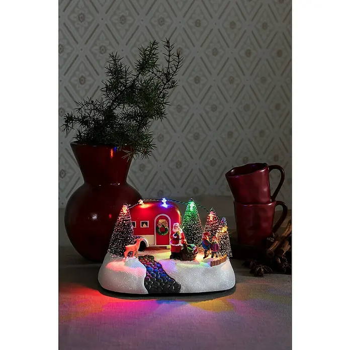 Konstsmide LED-Szenerie Wohnwagen - L x B x H: 13 x 18,5 x 10,5 cm, Mehrfarbig, Batteriebetrieben, LED - Weihnachtliche Dekoration mit einer beleuchteten Weihnachtsszene mit Santa und Wohnwagen, umgeben von festlicher Atmosphäre.