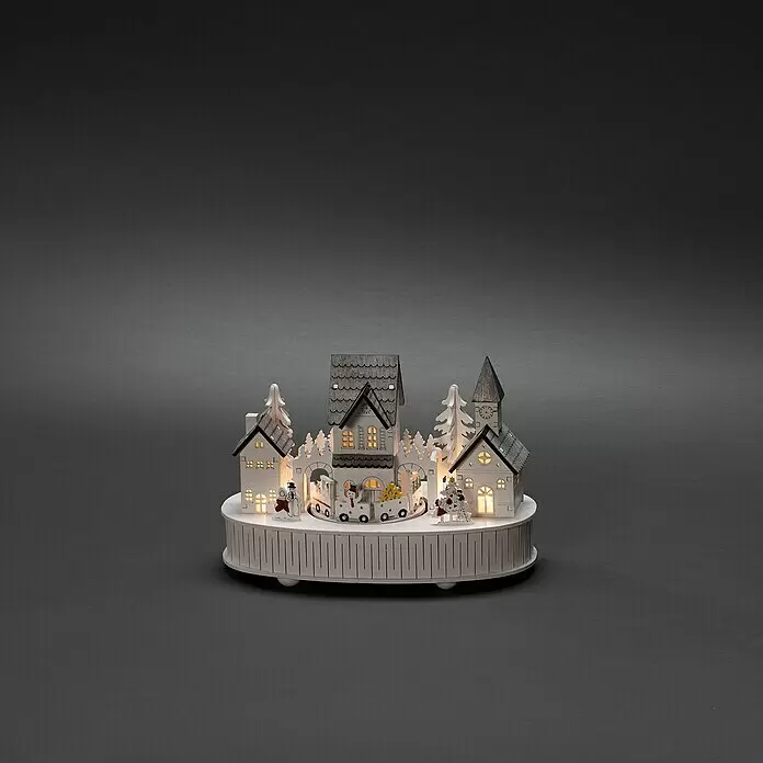 Konstsmide LED-Holzsilhouette - 12 x 22 x 15,5 cm, Weiß, Batteriebetrieben, Warmweiß, 0,3 W - Ein beleuchtetes Weihnachtsdorf aus weißem Holz mit Miniaturhäusern, Bäumen und einem Zug auf einem runden Sockel.