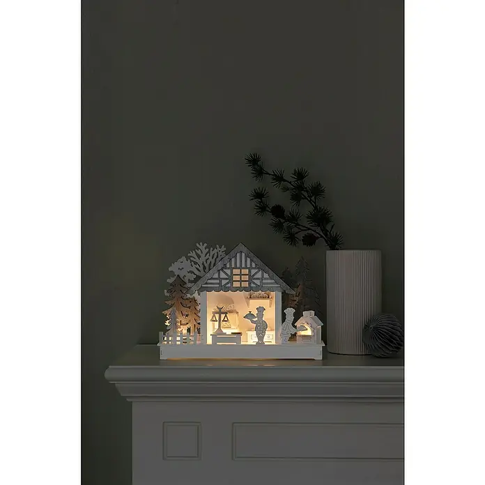 Konstsmide LED-Holzsilhouette - 30 x 7 x 21 cm, Batteriebetrieben, Warmweiß, 0,24 W - Holzgeschnitzte Weihnachtsbäckerei-Szene, beleuchtet, mit Bäumen und Dekorationen, die eine warme, festliche Atmosphäre schaffen.