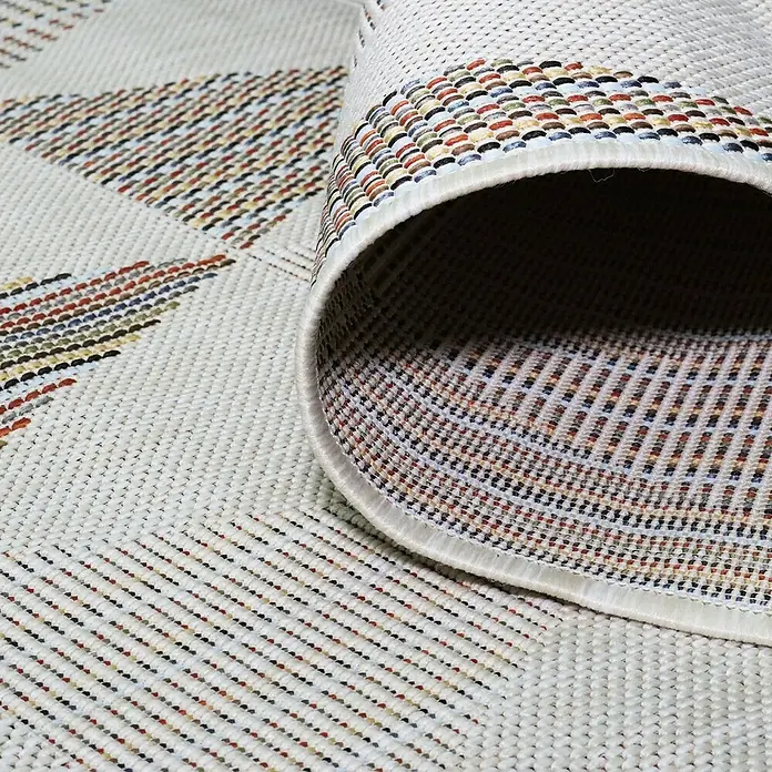 Alfombra exterior Rainbow - Beige, 170 x 120 cm - Primer plano de una alfombra enrollada que muestra patrones geométricos y tonos neutros, destacando la textura y el diseño.
