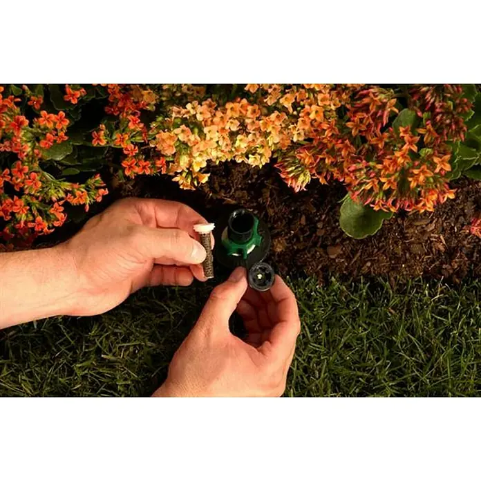 Orbit Aspersor oscilante Regulable - Altura: 10 cm, Polipropileno, Sector de riego por aspersión: 0 ° - 360 ° - Un hombre cambia una boquilla en un aspersor de césped para un riego óptimo. Riego preciso con el inserto de boquilla de rociado correcto.