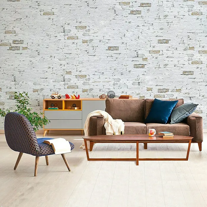 Verblendstein Pompeya Jet - 66,6 x 33,3 cm, Weiß, Steinoptik - Wohnzimmer-Szene mit braunem Sofa, Holzcouchtisch und einem farbenfrohen Sessel vor einer weißen Ziegelwand.