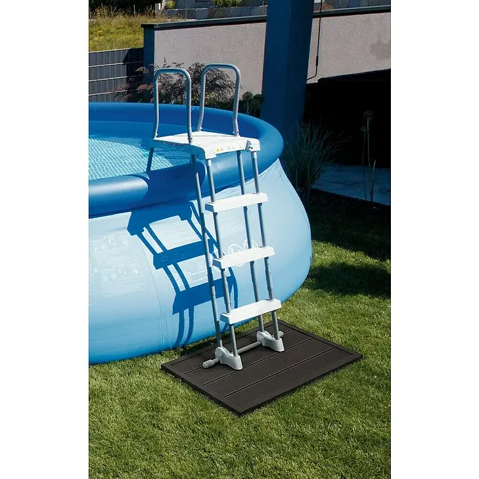 Bodenelement - 100 x 64 x 6,5 cm - Das Bild zeigt eine Poolleiter mit vier Stufen und Handläufen, die auf einer schwarzen Matte neben einem blauen Pool steht.