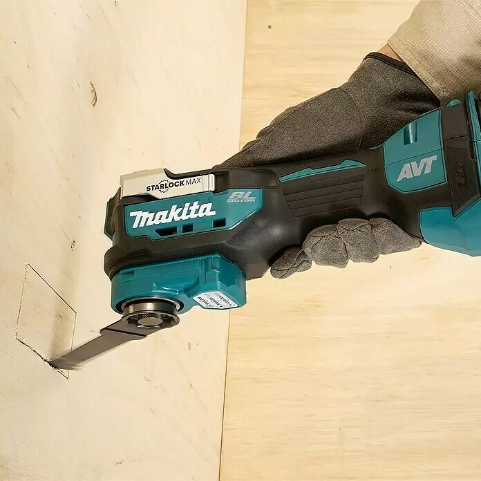 Makita LXT 18V Akku-Multifunktionswerkzeug DTM52 - 18 V, Ohne Akku - Türkis-schwarzes Makita Oszillierwerkzeug mit Klinge, die ein Quadrat in helles Holz schneidet, gehalten von einer behandschuhten Hand.