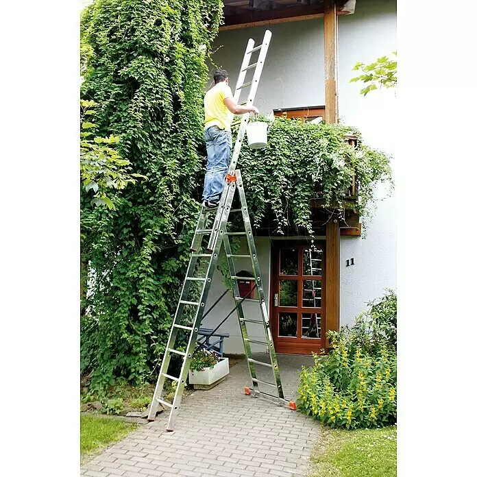 Krause Monto Mehrzweckleiter Tribilo - Arbeitshöhe: 7,65 m, Anzahl Tritte: 30 Stk., Belastbarkeit: 150 kg, Aluminium - Mann nutzt eine silberne Aluminium-Mehrzweckleiter als Stehleiter, um den oberen Balkon eines Hauses zu erreichen.