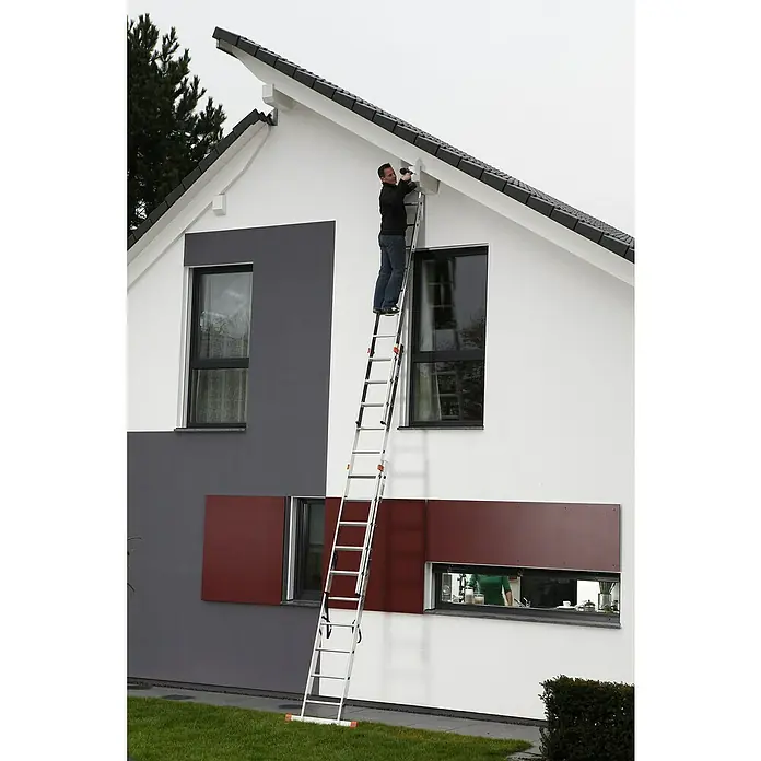 Krause Monto Mehrzweckleiter Tribilo - Arbeitshöhe: 7,65 m, Anzahl Tritte: 30 Stk., Belastbarkeit: 150 kg, Aluminium - Mann auf einer Aluminium-Mehrzweckleiter, der an einem Haus arbeitet, mit Blick auf Fenster, Dach und Garten.\n