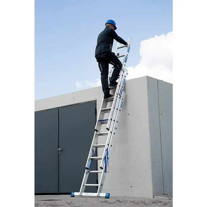 Krause Stabilo Mehrzweckleiter +S - Anzahl Tritte: 24 Stk., Arbeitshöhe: 5,95 m, Aluminium - Mann steigt auf einer KRAUSE Mehrzweckleiter auf ein Gebäude. Die Leiter ist aus Aluminium gefertigt und hat blaue Elemente.