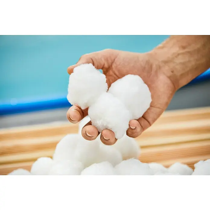 Malibu Filterbälle0,7 kg - Eine Hand hält eine Handvoll weiche, weiße Wattebäusche, die zum Reinigen oder für Bastelarbeiten geeignet sind.