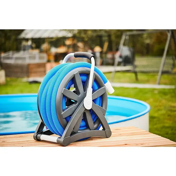 Malibu Schlauchtrommel mit Poolschlauch - Länge: 13 m, Nennweite Schlauchanschluss: Ø 38 mm - Eine blaue Poolschlauch-Aufrollvorrichtung steht auf einer Holzoberfläche, im Hintergrund ein Pool und Grün.