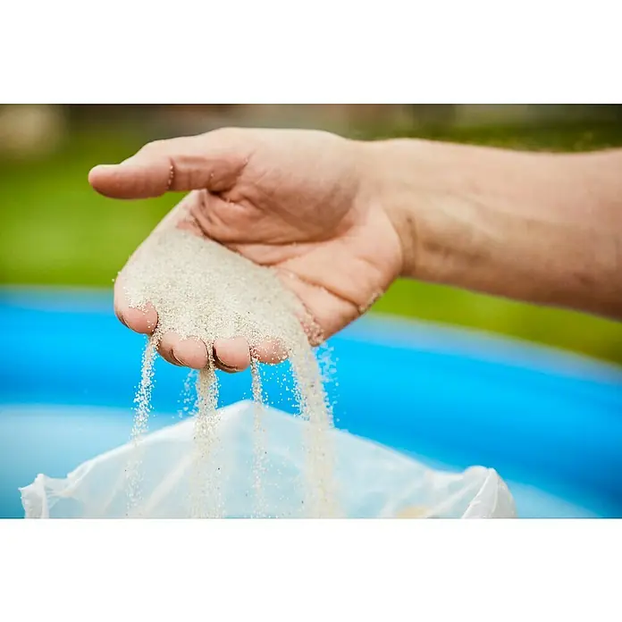 Min2C Aquasil-Filtersand - 25 kg, Körnung: 0,4 mm - 0,8 mm - Hand hält Sand, der durch die Finger rieselt. Das feine, helle Material ist gut erkennbar und rieselt in eine helle Tüte.