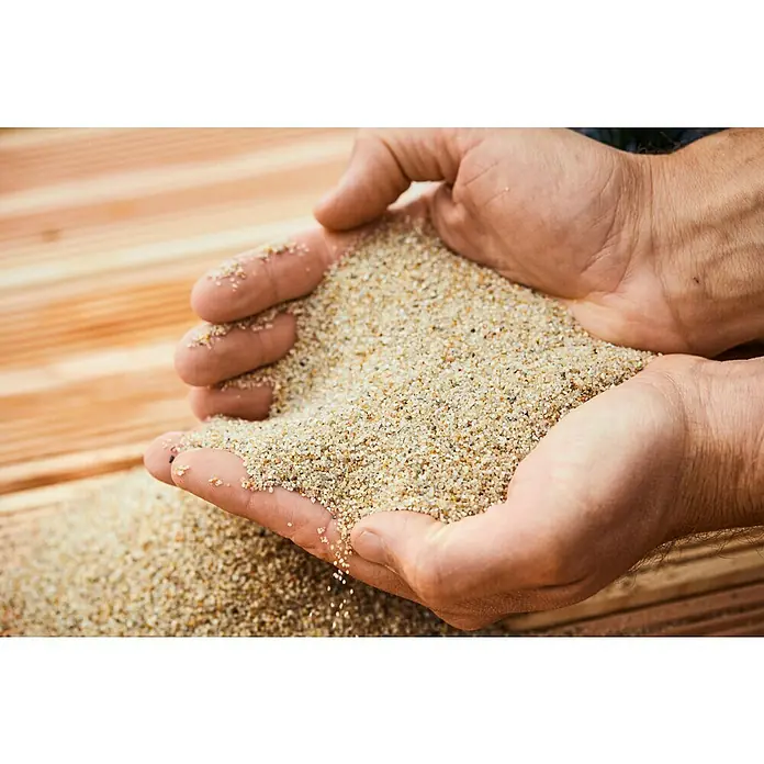Min2C Aquasil-Filtersand - 25 kg, Körnung: 0,7 mm - 1,2 mm - Nahaufnahme von Händen, die Sand halten und die Textur und Körnung des Sandes zeigen.