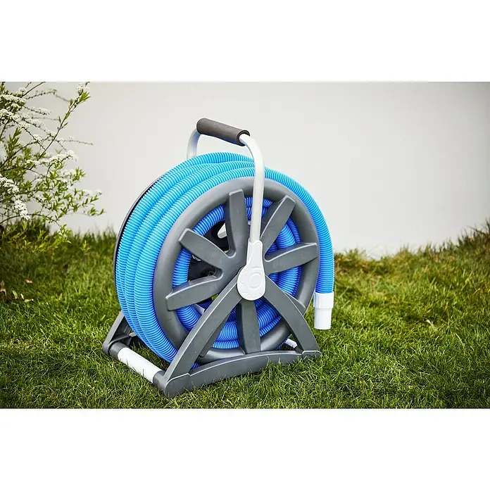 Malibu Schlauchtrommel mit Poolschlauch - Länge: 13 m, Nennweite Schlauchanschluss: Ø 38 mm - Ein aufgerollter, blauer Schwimmbadschlauch auf einer grauen Schlauchhaspel mit Griff steht auf einer grünen Wiese vor einer hellen Wand.