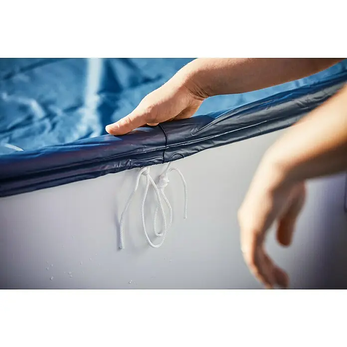 myPool Pool-Abdeckplane - Durchmesser: 300 cm, Kunststoff - Nahaufnahme einer Hand, die eine blaue Poolabdeckung mit weißen Kordeln auf einem weißen Poolrand befestigt, um den Pool sauber zu halten.