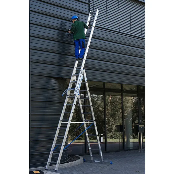Krause Stabilo Mehrzweckleiter +S - Anzahl Tritte: 36 Stk., Arbeitshöhe: 9,1 m, Aluminium - Eine Krause Vielzweckleiter ist vor einem Gebäude aufgestellt, auf der ein Arbeiter steht und etwas repariert.