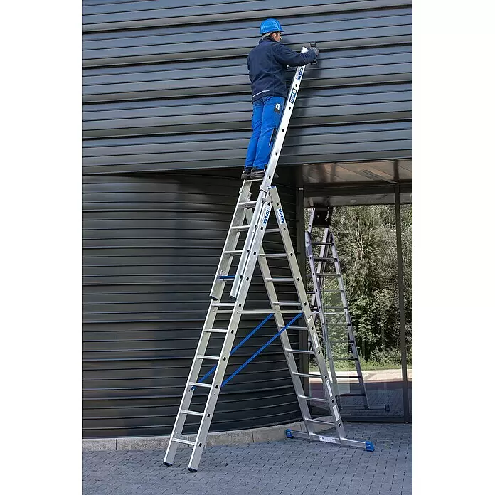 Krause Stabilo Mehrzweckleiter +S - Anzahl Tritte: 30 Stk., Arbeitshöhe: 7,5 m, Aluminium - Mann auf einer silbernen KRAUSE Aluminium-Mehrzweckleiter, der an einer dunkelgrauen Fassade arbeitet.