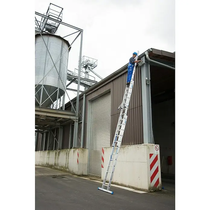 Krause Stabilo Mehrzweckleiter - Anzahl Tritte: 36 Stk., Arbeitshöhe: 9,3 m, Belastbarkeit: 150 kg, Aluminium - Eine Aluminium-Mehrzweckleiter wird für Reparaturen an einem Gebäude verwendet, wobei ein Mann auf ihr steht.