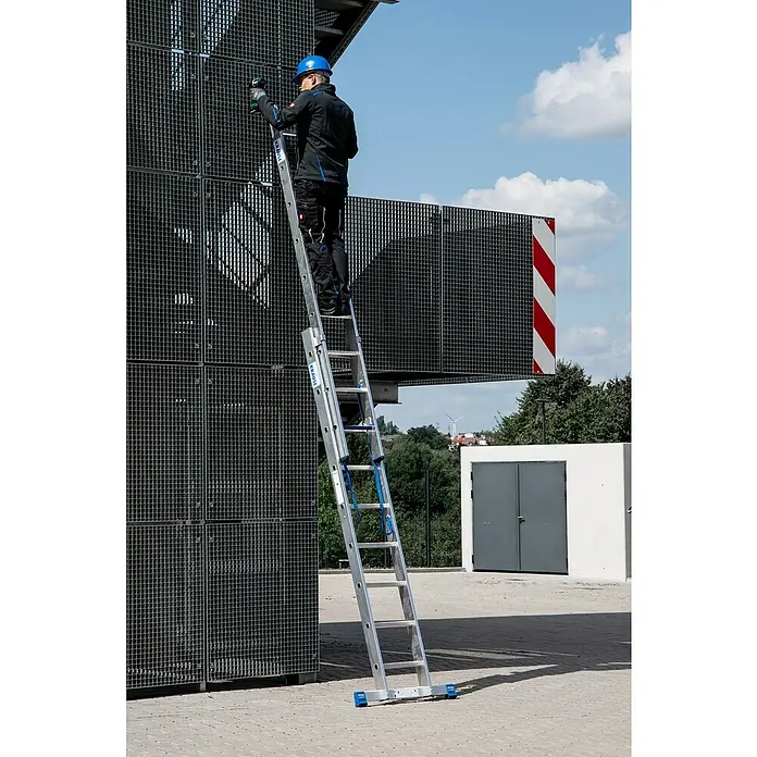 Krause Stabilo Mehrzweckleiter +S - Anzahl Tritte: 18 Stk., Arbeitshöhe: 5,15 m, Aluminium - Mann auf einer KRAUSE-Leiter, der an einer Gitterstruktur arbeitet. Die Leiter ist ausziehbar und steht sicher auf dem Boden.