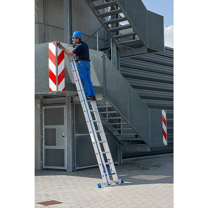Krause Stabilo Mehrzweckleiter +S - Anzahl Tritte: 24 Stk., Arbeitshöhe: 6,7 m, Aluminium - Ein Mann in Arbeitskleidung steht auf einer KRAUSE Leiter vor einem Gebäude und führt Arbeiten durch.