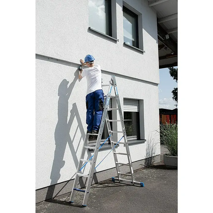 Krause Stabilo Mehrzweckleiter +S - Anzahl Tritte: 18 Stk., Arbeitshöhe: 5,15 m, Aluminium - Ein Mann auf einer Krause-Leiter bei der Arbeit an einer Hauswand. Die Leiter ist silbern und robust, ideal für Außenarbeiten.