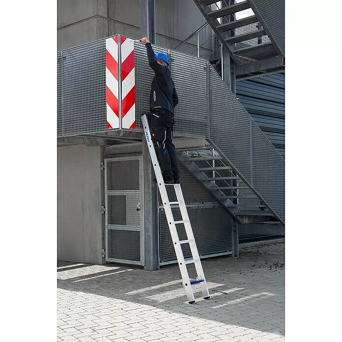 Krause Stabilo Schiebeleiter +S - Anzahl Tritte: 18 Stk., Arbeitshöhe: 5,15 m, Aluminium - Person auf silberner Aluminium-KRAUSE-Leiter, an Metallkonstruktion angelehnt, justiert etwas.