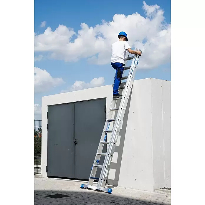 Krause Stabilo Mehrzweckleiter +S - Anzahl Tritte: 24 Stk., Arbeitshöhe: 6,7 m, Aluminium - Ein Mann steigt eine silberne KRAUSE Mehrzweckleiter hinauf, die an einem hellgrauen Gebäude unter blauem Himmel lehnt.