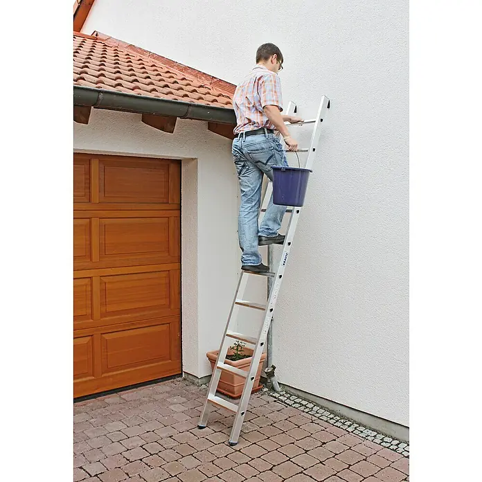 Krause Stabilo Anlegeleiter + S - Anzahl Tritte: 10 Stk., Arbeitshöhe: 3,6 m, Aluminium - Mann auf einer Krause Leiter mit Eimer, die Leiter lehnt an einer weißen Wand. Sichere Steighilfe für Haus und Garten.