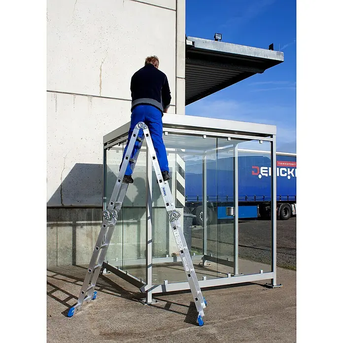 Krause Stabilo Mehrzweckleiter - Anzahl Tritte: 16 Stk., Arbeitshöhe: 5,5 m, Aluminium - Eine Teleskopleiter von KRAUSE steht vor einem gläsernen Unterstand, während eine Person darauf arbeitet. Ideal für Wartungsarbeiten in der Höhe.