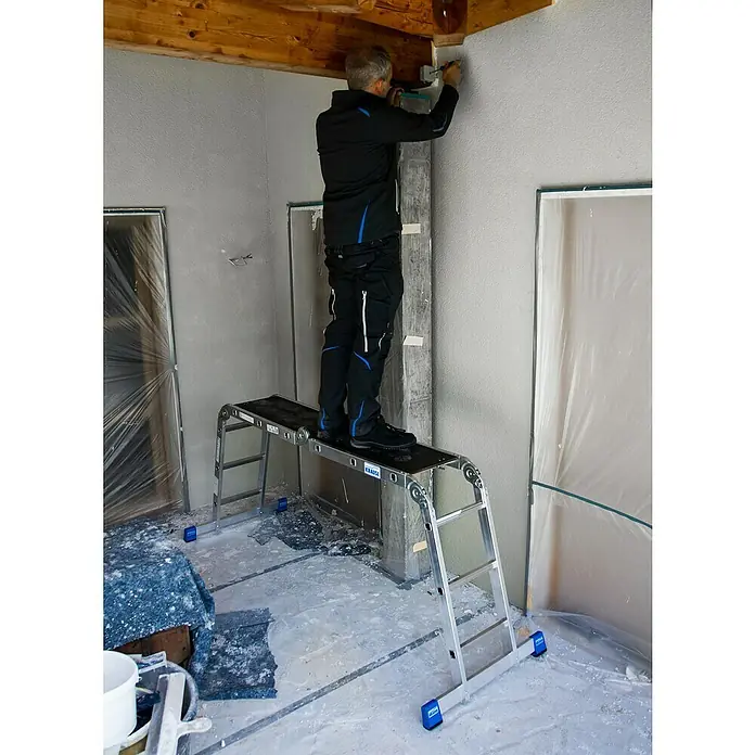 Krause Stabilo Mehrzweckleiter - Anzahl Tritte: 12 Stk., Arbeitshöhe: 4,4 mm, Aluminium - Handwerker steht auf einer Krause Arbeitsbühne und arbeitet an einer Wand in einem Raum mit Holzdecke. Malerarbeiten mit sicheren Tritt.