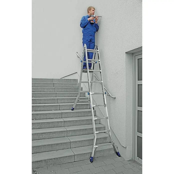 Krause Stabilo Teleskopleiter - Anzahl Tritte: 20 Stk., Arbeitshöhe: 6,05 m, Aluminium - Ein Handwerker bohrt mit einer Klappleiter an einer Wand. Die vielseitige Leiter bietet Flexibilität für Arbeiten in unterschiedlichen Höhen.