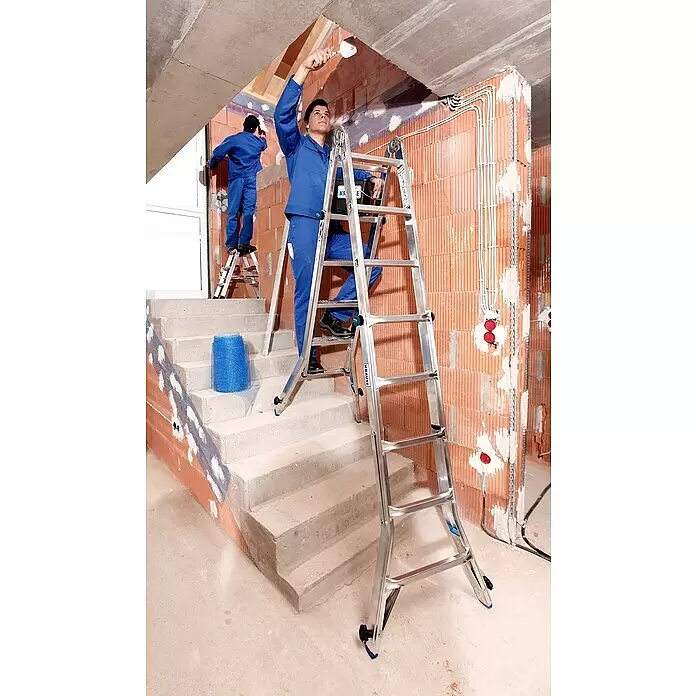 Krause Stabilo Teleskopleiter mit 4 Holmverlängerungen - Anzahl Tritte: 20 Stk., Arbeitshöhe: 6,05 m, Aluminium - Zwei Arbeiter nutzen Aluminiumleitern für Bauarbeiten in einem Rohbau, wobei einer Putz aufträgt.