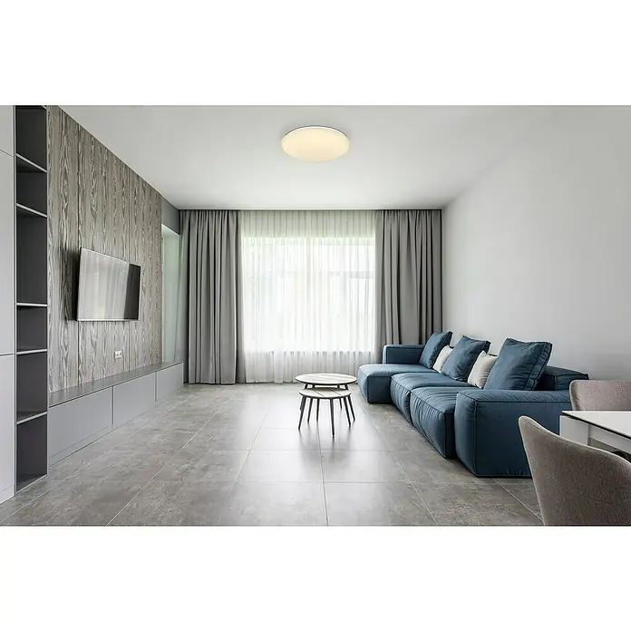 Globo Atreju I Deckenleuchte rund ATREJU I - 24 W, Ø x H: 410 mm x 10,5 cm, Weiß, Sonstige - Modernes Wohnzimmer mit blauem Sofa, grauen Vorhängen und einem runden Deckenlicht. Das Zimmer strahlt eine ruhige und stilvolle Atmosphäre aus.