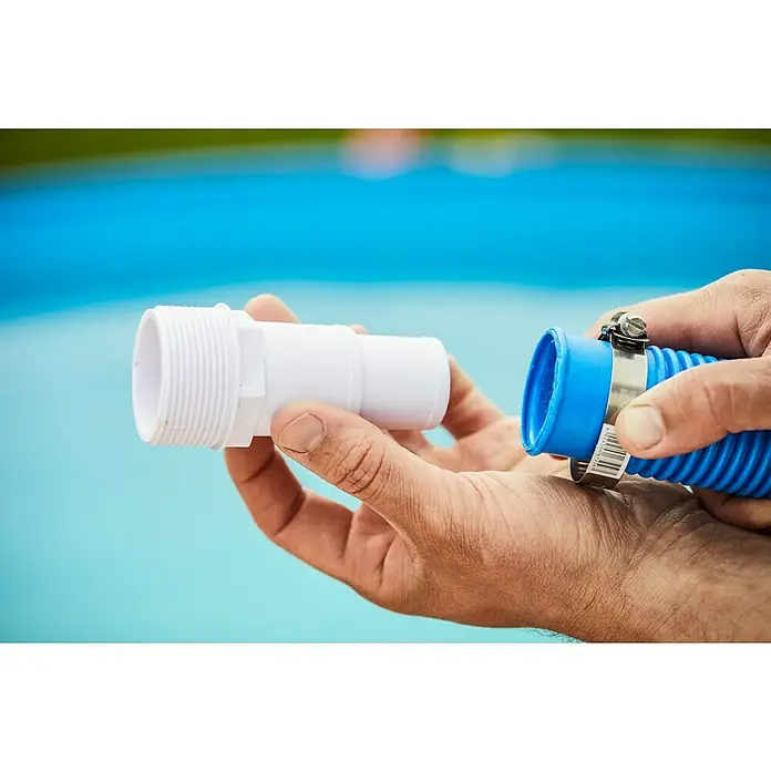 Malibu Schlauchverbinder - Durchmesser: 32 mm - 38 mm - Ein weißer PVC-Adapter und ein blaues Schwimmbadrohr werden von Händen vor einem blauen Schwimmbadhintergrund gehalten.