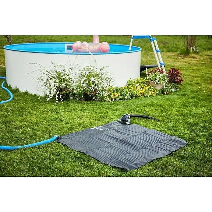 Intex Solarmatte - 120 x 120 cm, 1.250 l/h - Schwimmbadheizmatte auf dem Rasen neben einem Pool mit Leiter und Blumen. Die Matte ist grau und mit einem Schlauch verbunden.