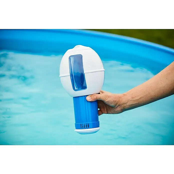 Malibu Schwimmdosierer - Weiß - Eine Person hält einen Poolchemikalien-Dispenser über einem blauen Pool. Der Dispenser ist weiß und blau.