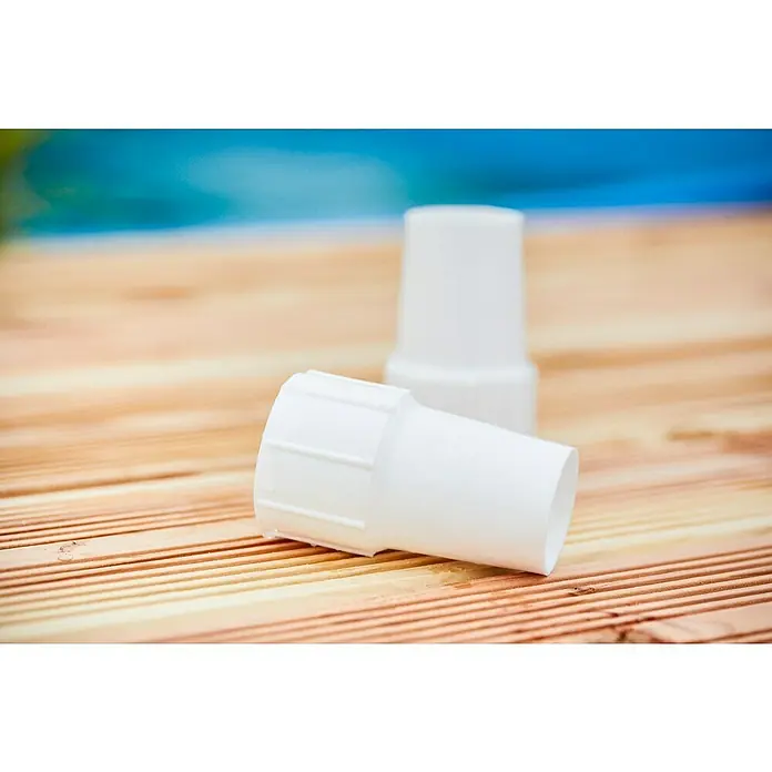 Malibu Schlauchverbinder - Durchmesser: 32 mm - Zwei weiße PVC-Rohrverbinder liegen auf einer Holzoberfläche, im Hintergrund ist eine unscharfe blaue Fläche zu sehen.