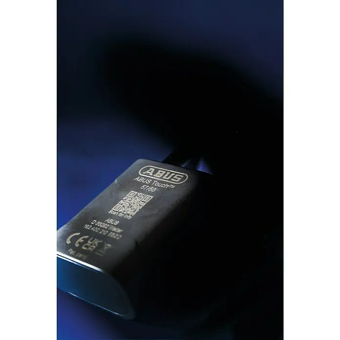 Abus Candado 57/45 - Sensor de dedo, Zinc fundido, L x An x Al: 23 x 45 x 95 mm - Primer plano de un candado ABUS Touch™ 57/50 con código QR e información de la empresa sobre un fondo oscuro.