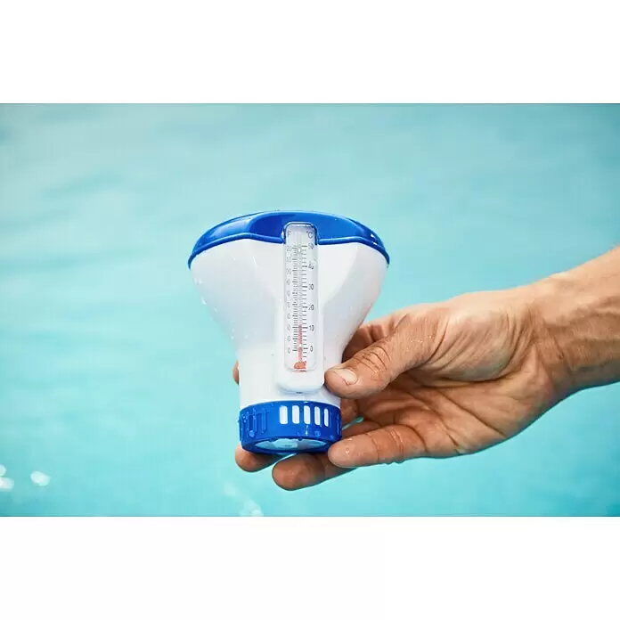 Malibu Schwimmdosierer - Blau - Weiße und blaue schwimmende Poolthermometer in einer Hand vor hellblauem Poolhintergrund, zeigt die Temperatur an.