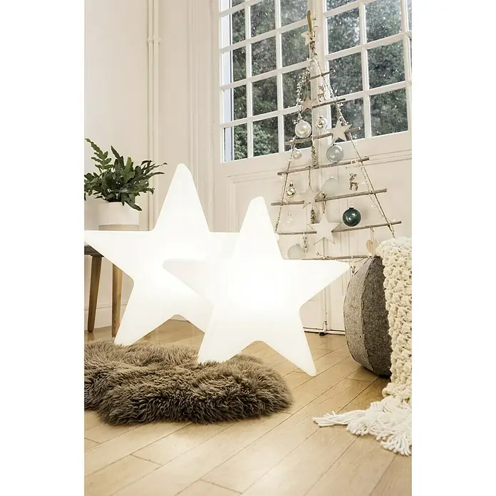 8 Seasons Design Shining LED-Stern Star - Weiß, Durchmesser: 80 cm, Polyethylen, 9 W - Leuchtende Sternlampen auf einem Fellteppich, neben einem dekorativen Weihnachtsbaum im Raum.