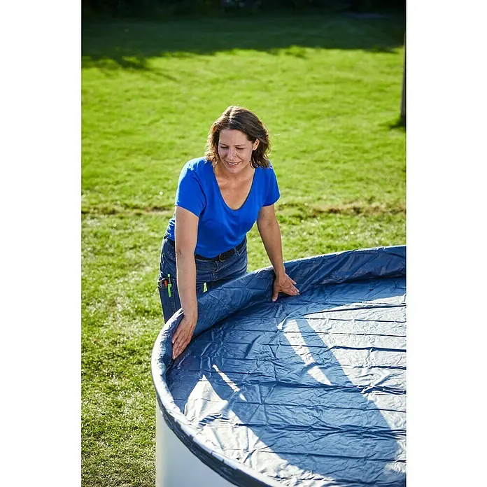 myPool Pool-Abdeckplane - Durchmesser: 300 cm, Kunststoff - Eine Frau installiert eine blaue Poolfolie in einem runden Pool vor einem grünen Rasen, um das Schwimmbecken vor Schmutz zu schützen.