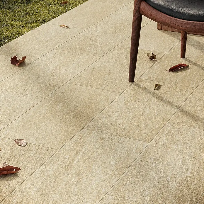 Atlas Concorde Solution Lane Feinsteinzeugfliese - 30 x 60 cm, Desert, Matt - Ein ebenerdiger Außenbereich mit hellen, rechteckigen Terrassenplatten und vereinzelten Herbstblättern, die für eine natürliche Note sorgen.