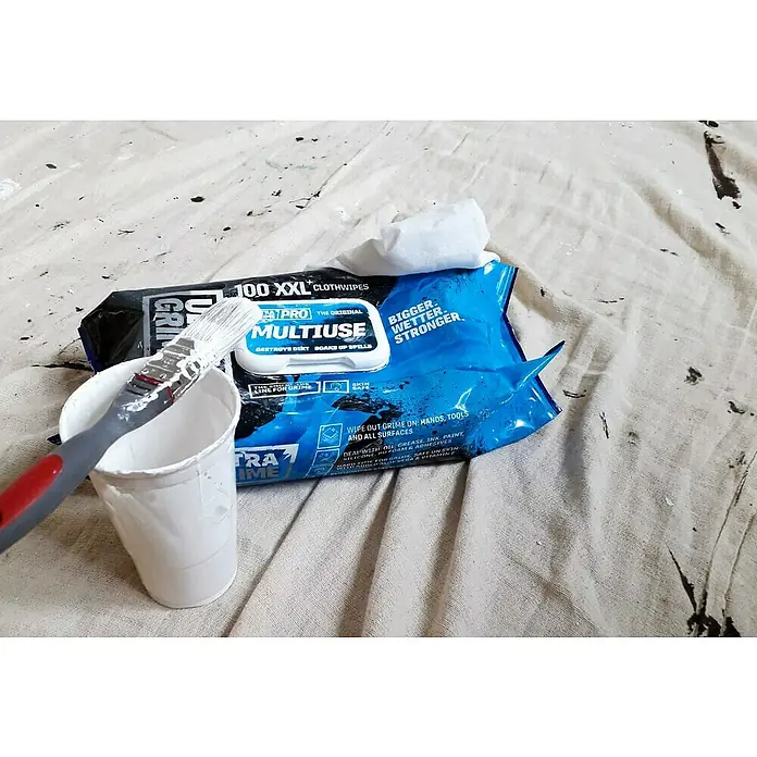 Feuchte Reinigungstücher Ultra Grime - 100 Stk. - Ein Pinsel liegt auf einer Dose Farbe, daneben eine Packung "Ultra Grime" Reinigungstücher auf einer bemalten Plane.